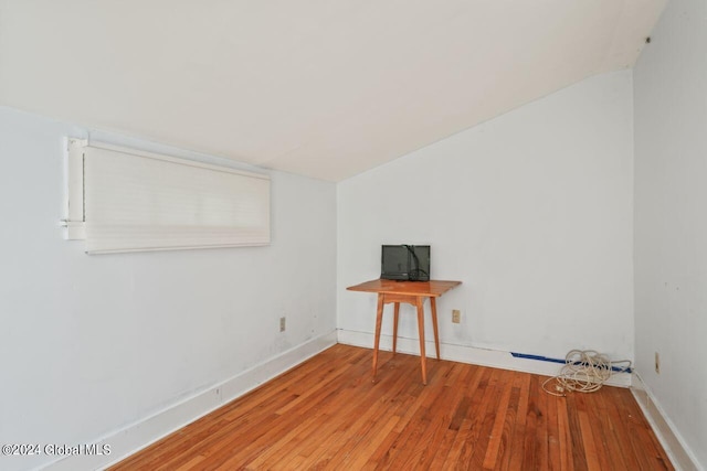 spare room with hardwood / wood-style flooring, baseboards, and vaulted ceiling