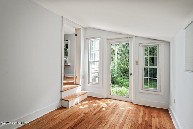 doorway to outside with vaulted ceiling, baseboards, and light wood finished floors