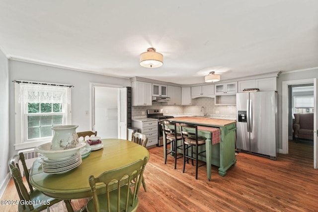 dining area featuring crown molding, baseboards, and dark wood-style flooring