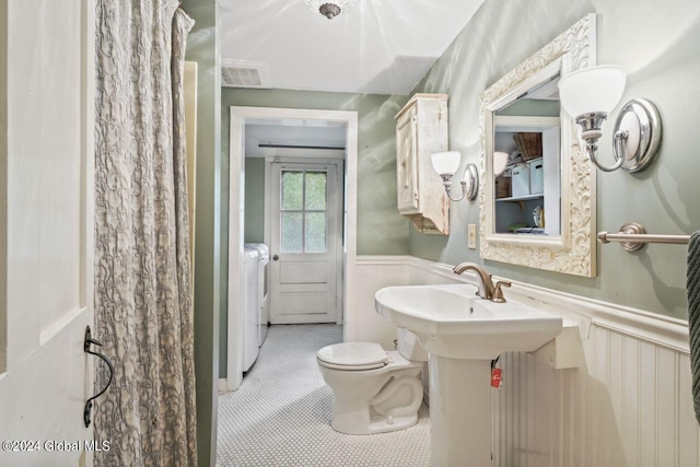 bathroom with visible vents, wainscoting, washer and dryer, and toilet