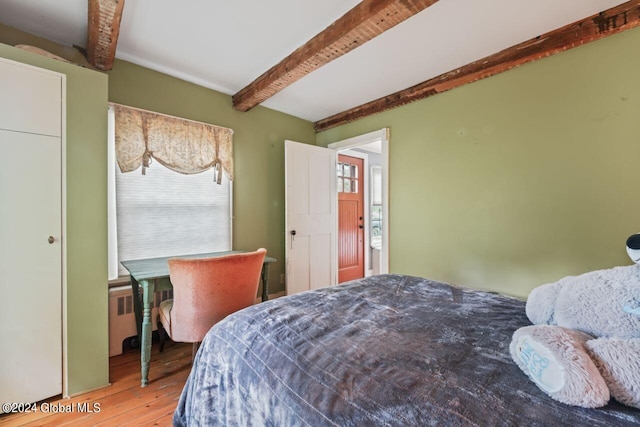 bedroom with beam ceiling, radiator, and wood finished floors