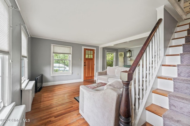 living area with stairway, wood-type flooring, and baseboards