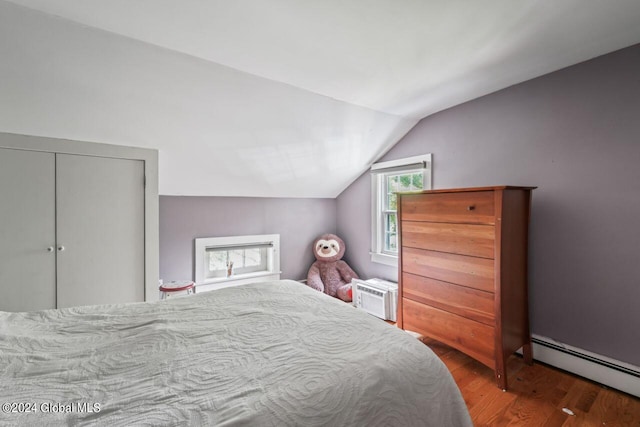 bedroom featuring a baseboard heating unit, lofted ceiling, and wood finished floors