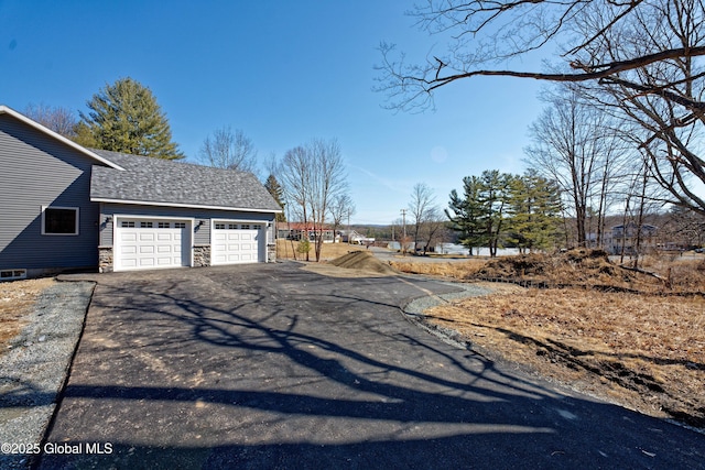 view of property exterior featuring aphalt driveway, stone siding, and an attached garage