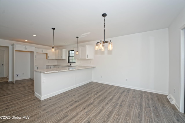 kitchen with a sink, a peninsula, baseboards, and wood finished floors