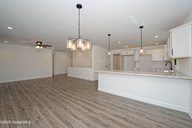 kitchen with recessed lighting, ceiling fan with notable chandelier, white cabinetry, and wood finished floors