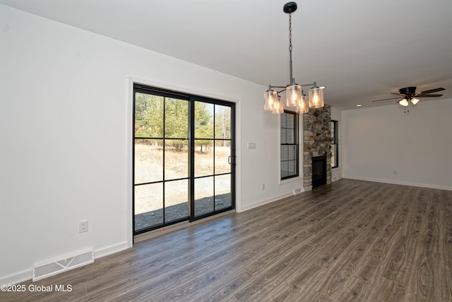 unfurnished living room featuring visible vents, baseboards, dark wood finished floors, and ceiling fan with notable chandelier