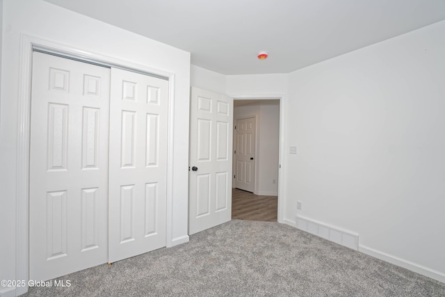 unfurnished bedroom with visible vents, carpet floors, baseboards, and a closet