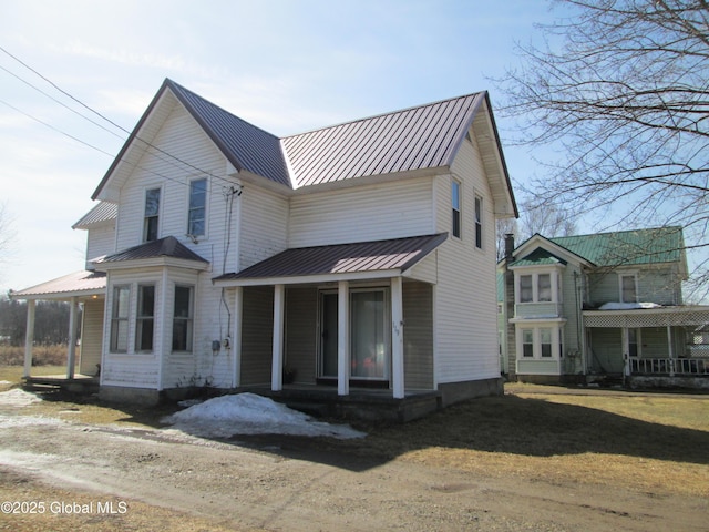view of front of house featuring a front yard, a porch, driveway, and metal roof