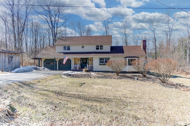 view of front facade with driveway, covered porch, and a chimney