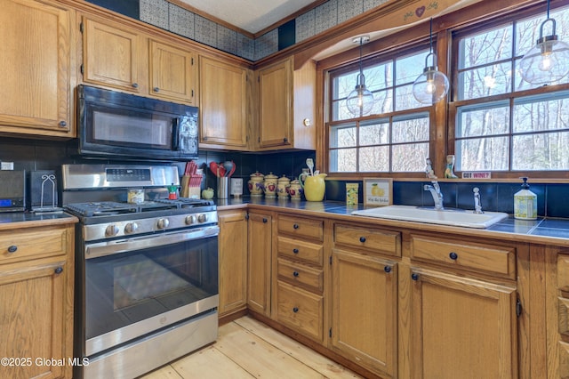 kitchen featuring stainless steel gas range oven, a wealth of natural light, black microwave, and a sink