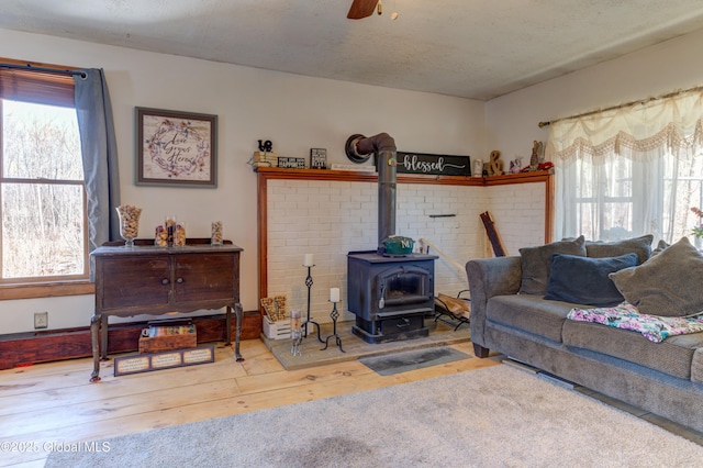 living area featuring hardwood / wood-style floors, a textured ceiling, a wood stove, and ceiling fan