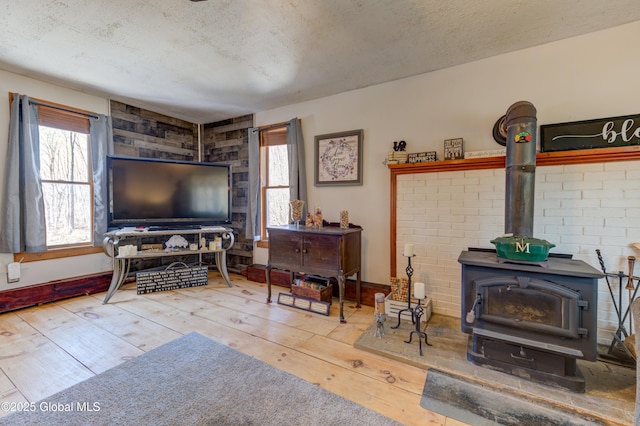 living area with a wealth of natural light, a textured ceiling, a wood stove, and hardwood / wood-style flooring