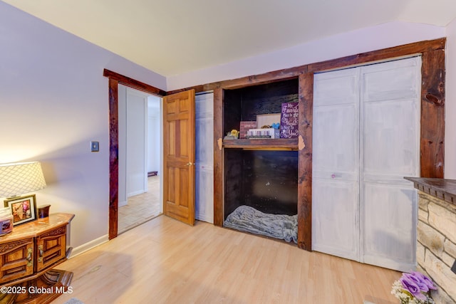 bedroom with baseboards, multiple closets, and wood finished floors