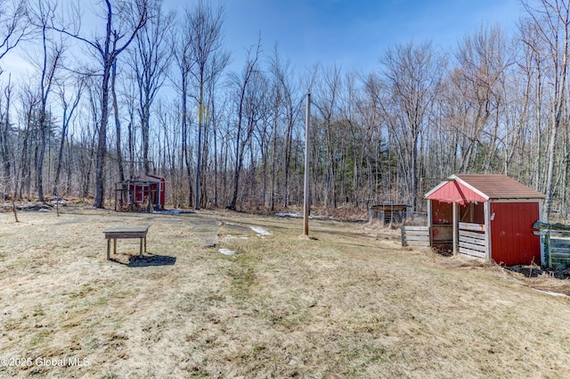 view of yard with a view of trees, an outdoor structure, and a playground