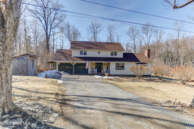 view of front of property with a chimney, an attached garage, a porch, and driveway