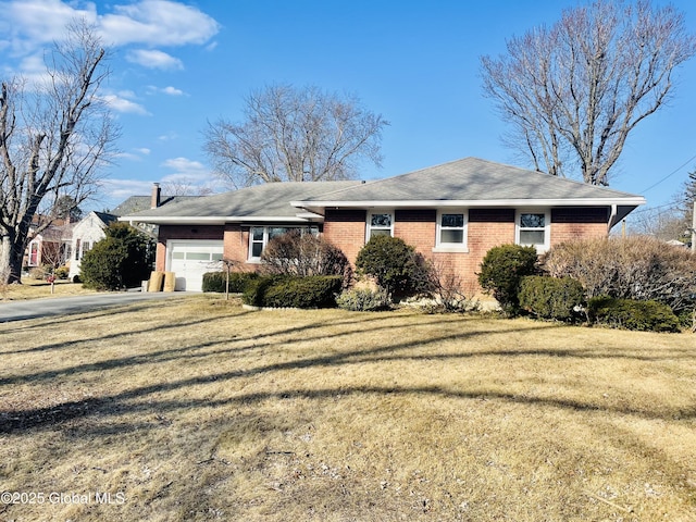 exterior space featuring brick siding, an attached garage, driveway, and a front lawn