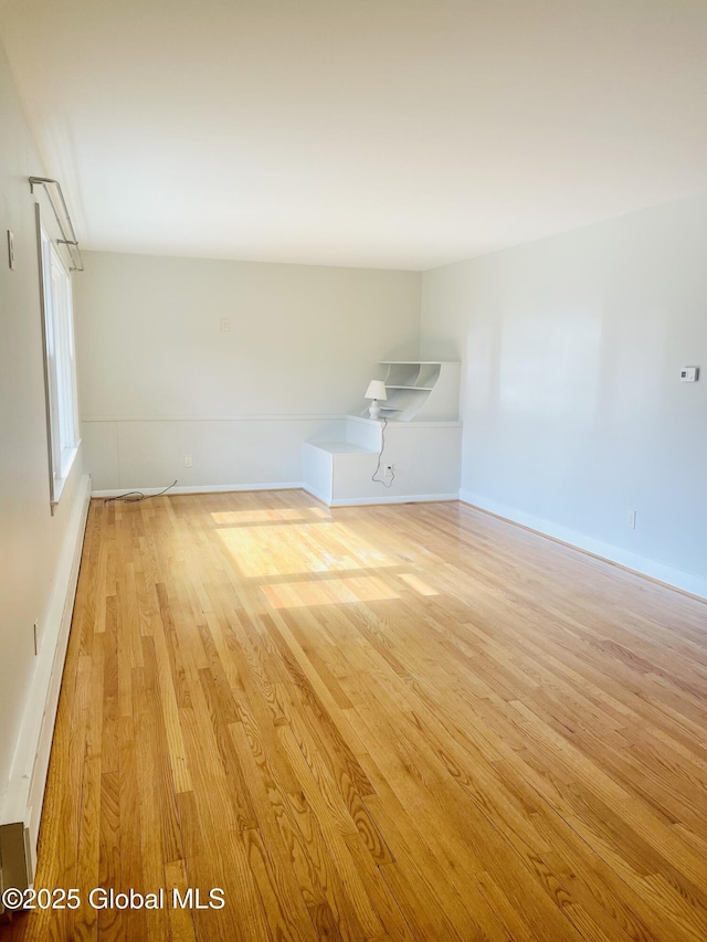 spare room with wood finished floors, baseboards, and a baseboard radiator