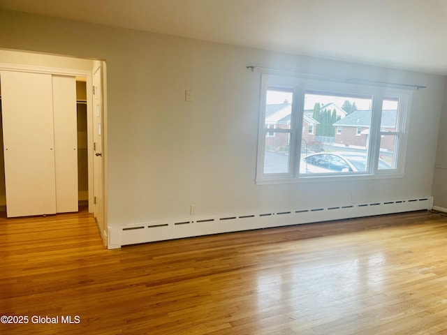 empty room with a baseboard heating unit and wood finished floors