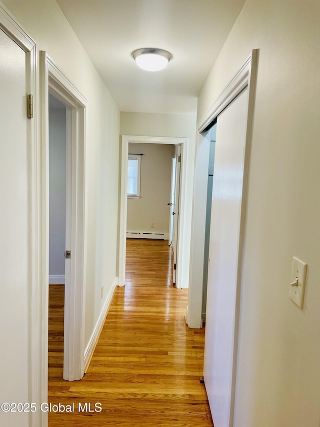 corridor featuring light wood-style floors, baseboards, and a baseboard radiator