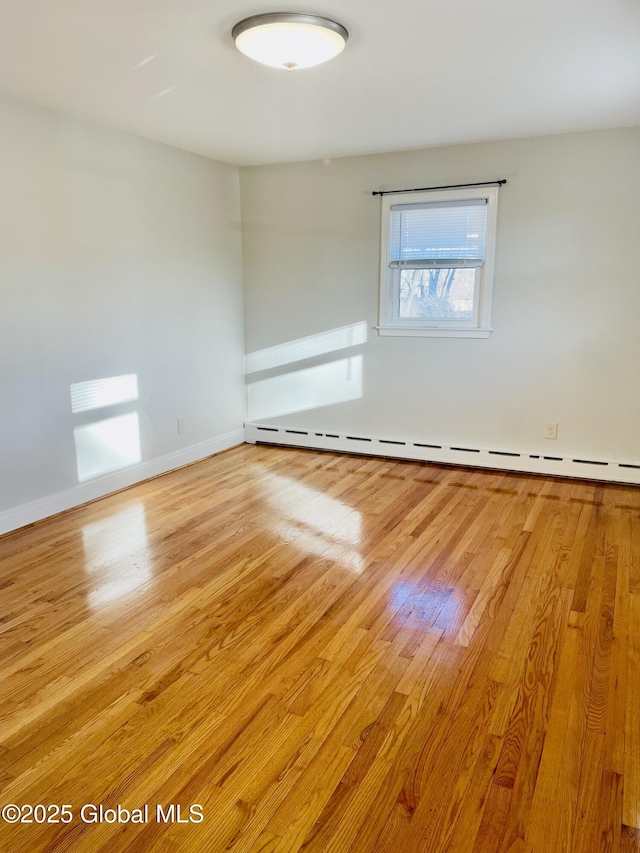 empty room with baseboards, light wood-type flooring, and baseboard heating