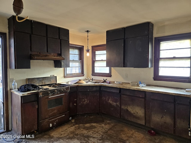 kitchen featuring under cabinet range hood, decorative light fixtures, range with gas stovetop, and light countertops