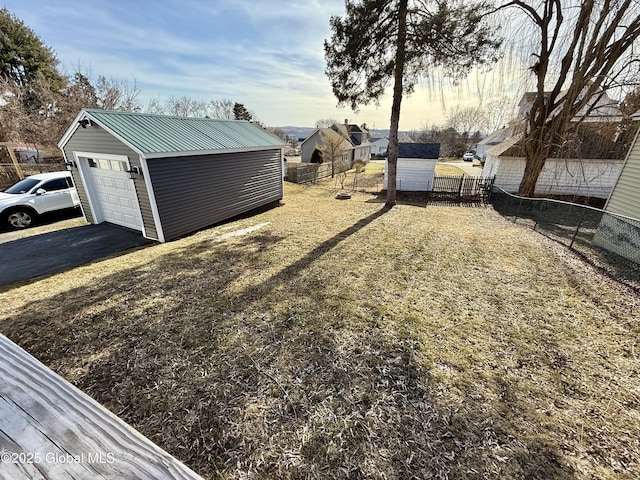 view of yard featuring an outbuilding, driveway, a garage, and fence