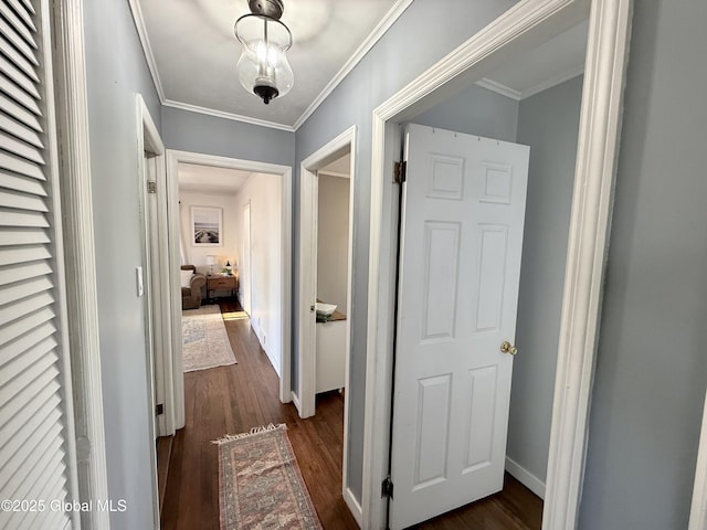 corridor featuring baseboards, ornamental molding, and dark wood-style flooring