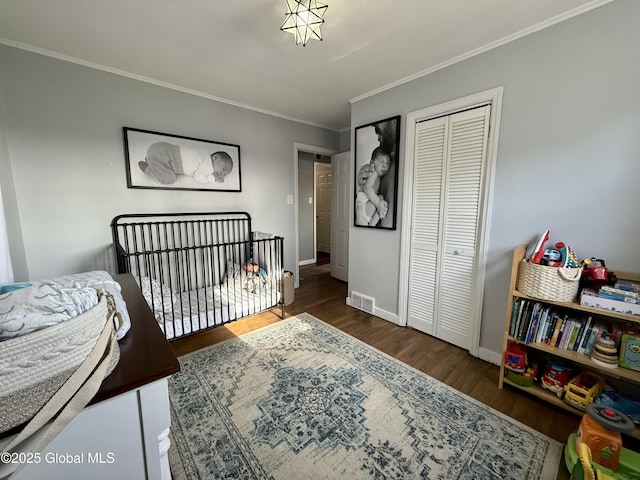 bedroom featuring visible vents, wood finished floors, a closet, crown molding, and baseboards