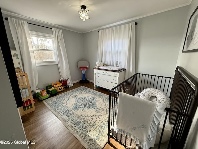 bedroom featuring baseboards, wood finished floors, and ornamental molding