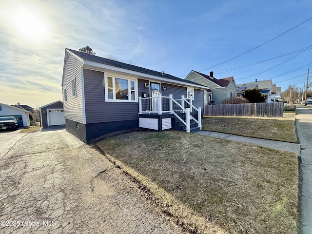 view of front of house featuring a garage, a front yard, an outdoor structure, and fence