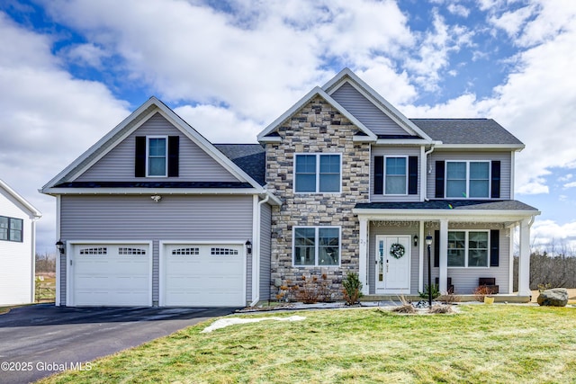 view of front facade with roof with shingles, an attached garage, a front lawn, stone siding, and aphalt driveway