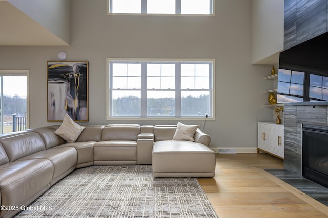 living room featuring visible vents, plenty of natural light, a fireplace, and light wood-style flooring