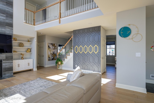 living area with stairway, an accent wall, baseboards, and wood finished floors