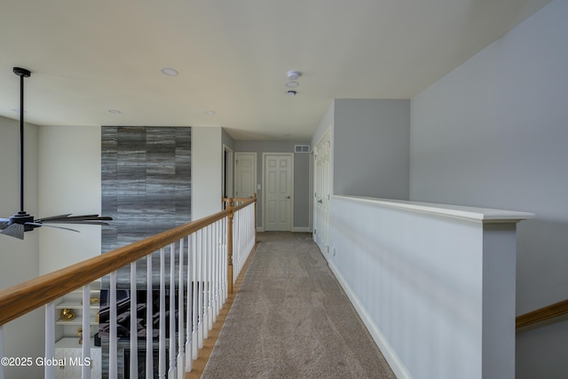 corridor with visible vents, light colored carpet, and baseboards