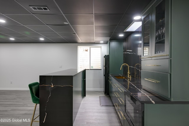 kitchen with wood finished floors, visible vents, freestanding refrigerator, and a sink