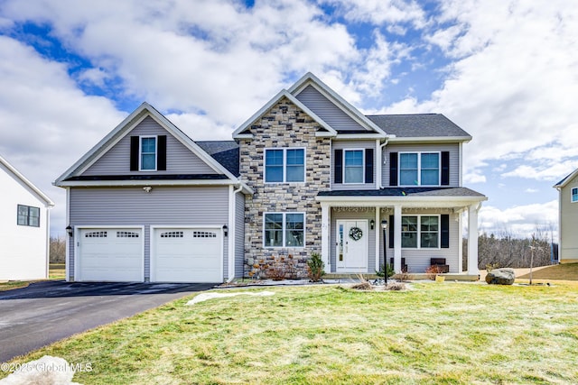 view of front of home featuring a garage, stone siding, a front lawn, and driveway