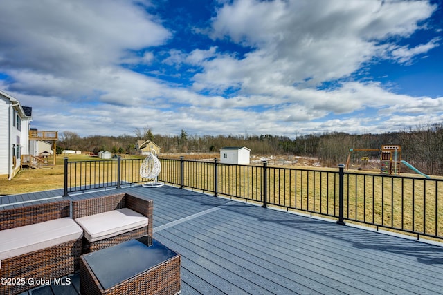 wooden terrace featuring an outbuilding, a playground, a storage unit, and a yard