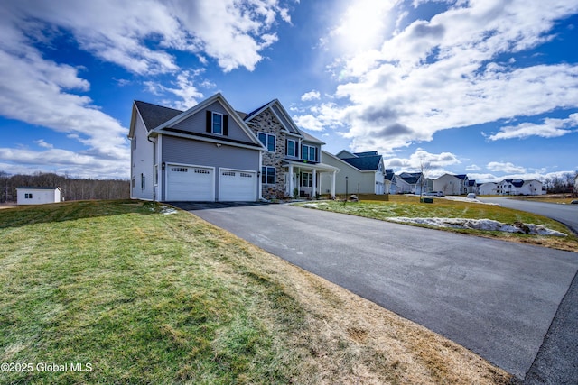 traditional home featuring aphalt driveway, a residential view, a front lawn, and a garage