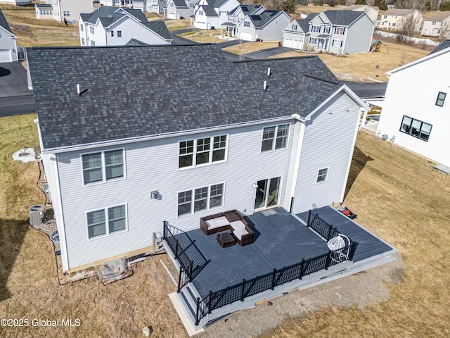 back of house featuring a residential view, a lawn, a wooden deck, and roof with shingles