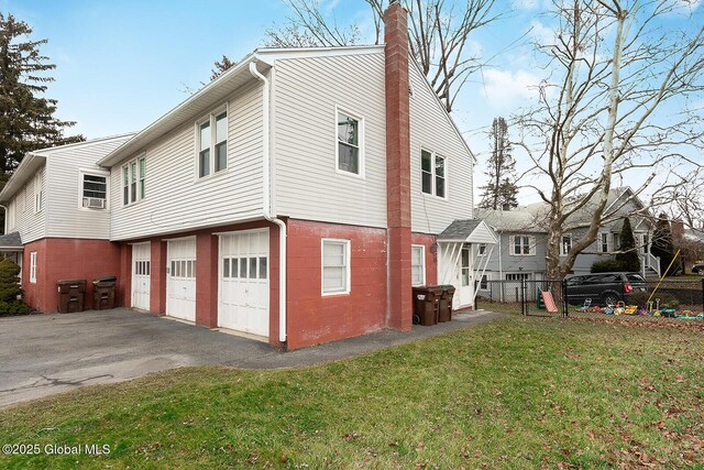 view of property exterior featuring fence, an attached garage, a chimney, aphalt driveway, and a lawn