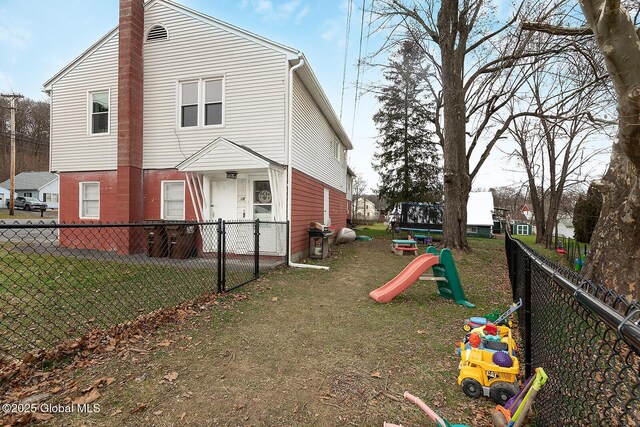 back of house featuring a chimney, fence private yard, a playground, and a yard