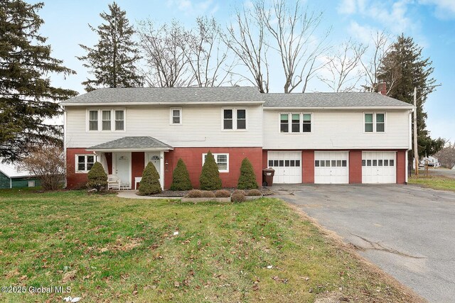 view of front of house featuring aphalt driveway, an attached garage, and a front yard