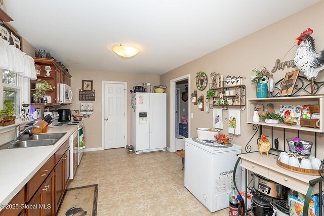 kitchen with open shelves, light countertops, brown cabinets, white appliances, and a sink
