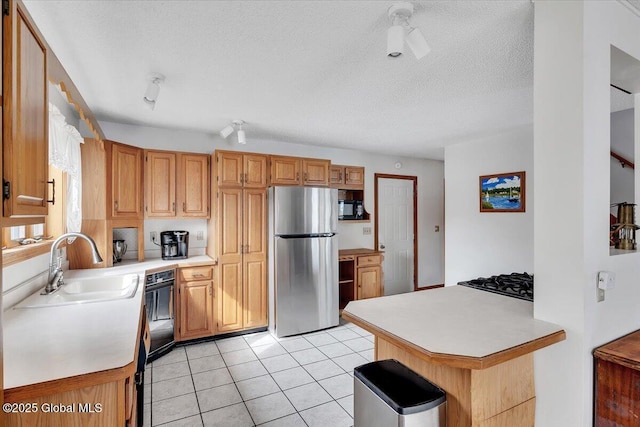 kitchen featuring light countertops, freestanding refrigerator, black microwave, and a sink