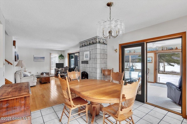 dining area featuring light tile patterned flooring, a textured ceiling, and an inviting chandelier
