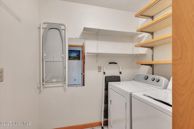 washroom with washing machine and clothes dryer, laundry area, a textured ceiling, and baseboards