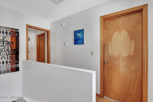 corridor with an upstairs landing and a textured ceiling