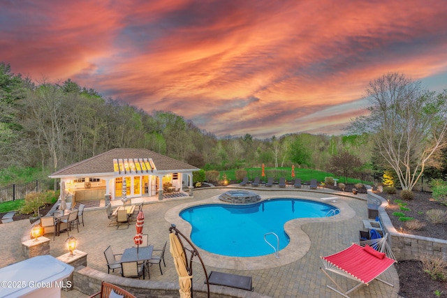 1014 Catherines Woods Dr, Niskayuna, NY 12309 - pool at dusk featuring an outdoor fire pit, an in-ground hot tub, a patio area, and an outdoor structure