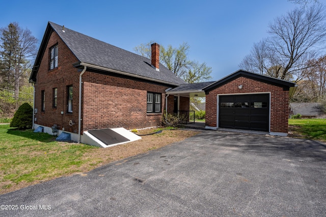 view of front facade featuring aphalt driveway, a chimney, brick siding, a shingled roof, and an attached garage